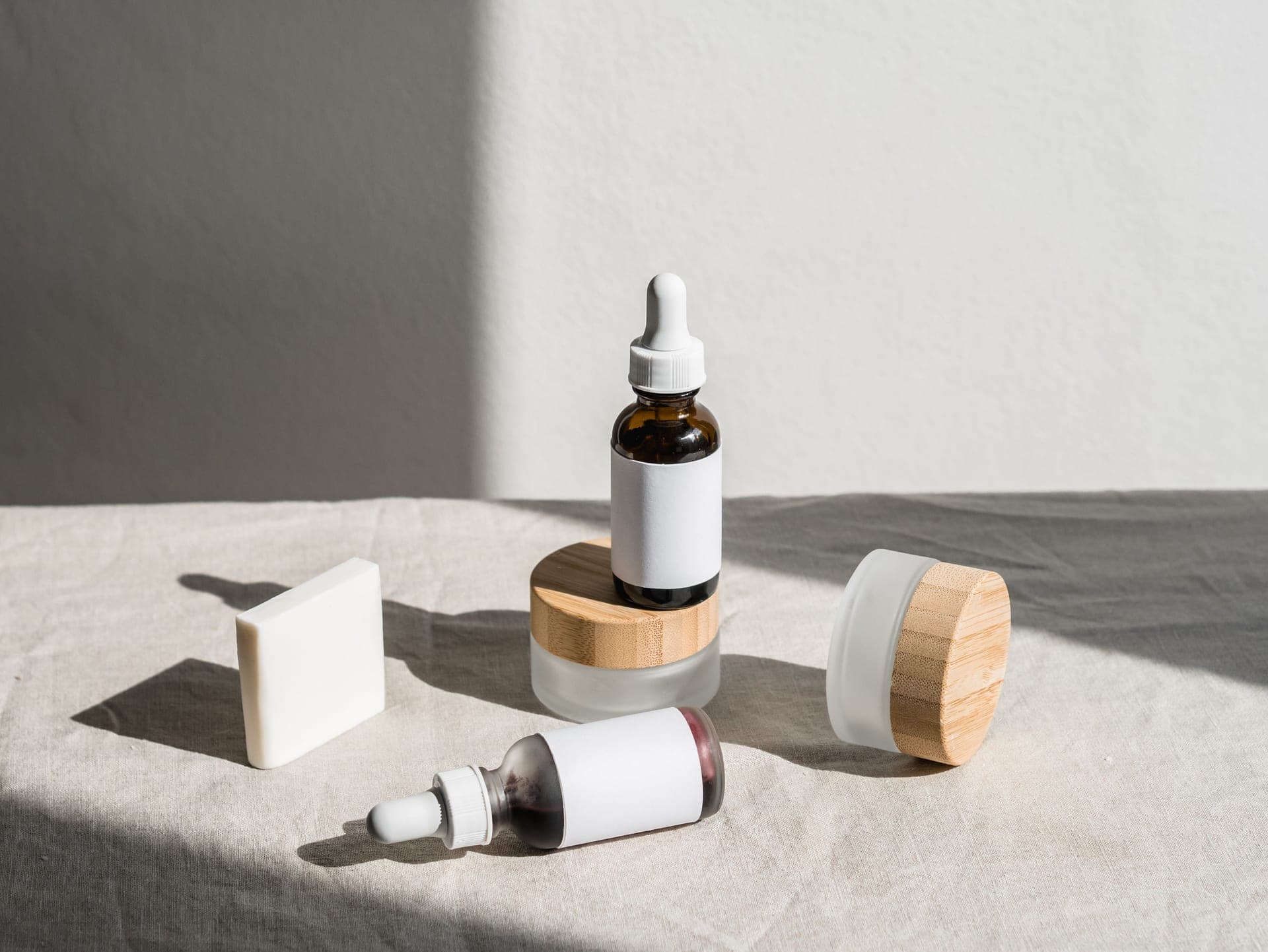 Amber glass dropper bottles and serum textures arranged on a warm paper-toned surface in soft light